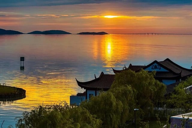 Colorful water sunset on Lake Tai, Suzhou - bridge and islands visible on the horizon.