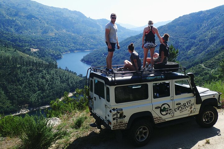 Explore the stunning landscapes of Peneda-Gerês National Park where friends gather atop a vehicle savoring the breathtaking views of mountains and serene waters perfect for adventure seekers.