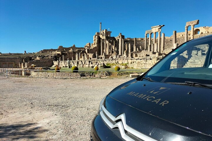 The minivan taximami photographed with the archaeological site of Dougga in the background